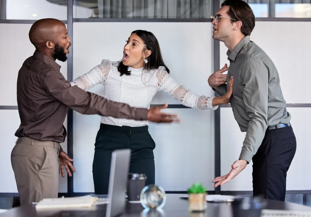 Three people appear to be engaged in a heated discussion in an office setting, with expressions of concern and frustration.